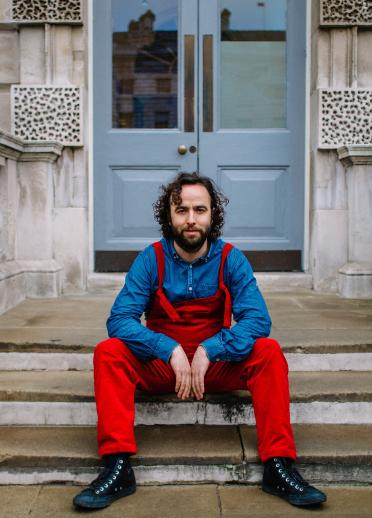 Daf James sits outside a double front door on some steps