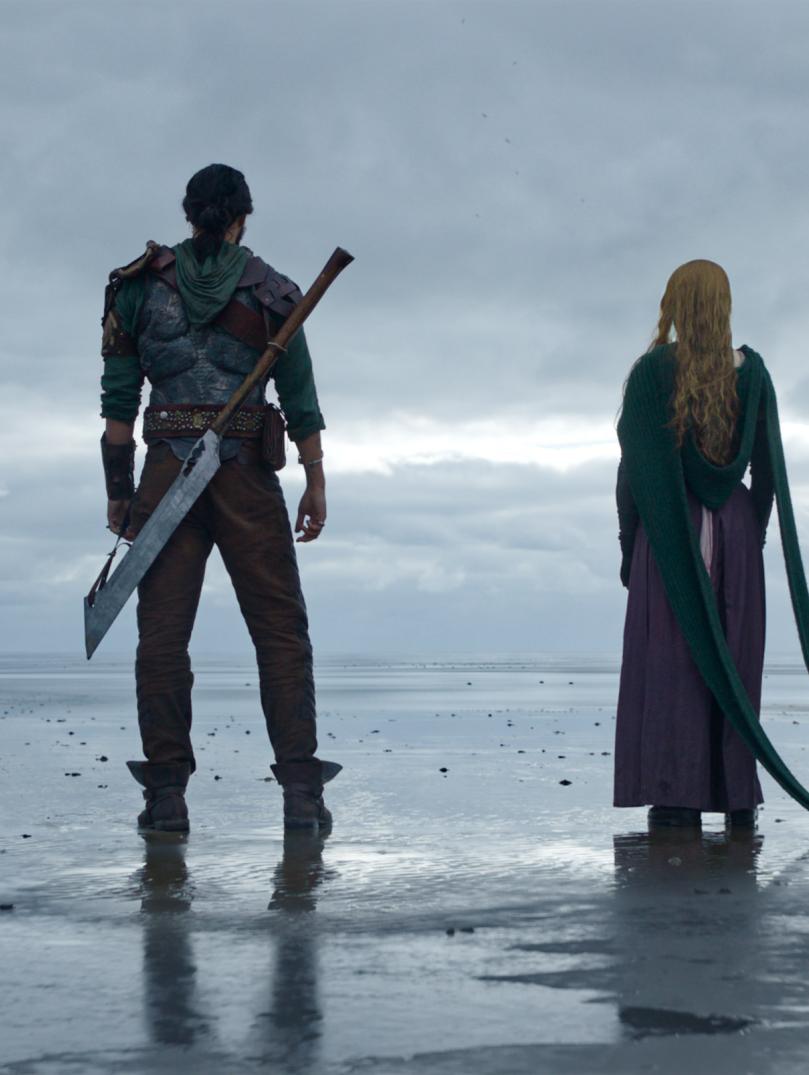 Four people stand on the end of the shore looking out to sea