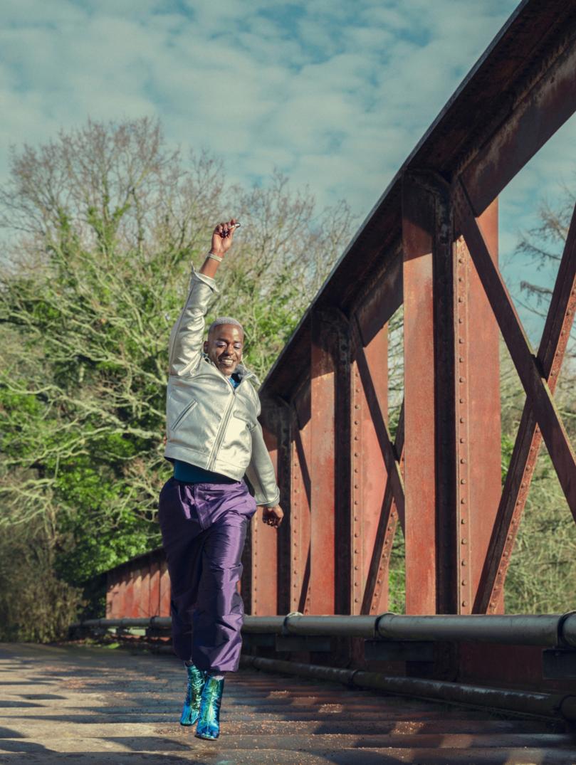 Sex Education cast member jumps up as he crosses a bridge in a scene from Sex Education